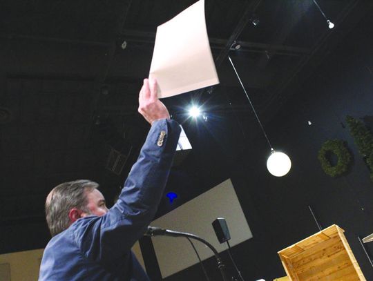 Attorney Justin Schrader lifts a paper detailing a medical study as part of his opposition to the proposed quarry before Asphalt Inc. representative Ben Liggett Dec. 10 during the public meeting in Burnet. Raymond V. Whelan/Bulletin