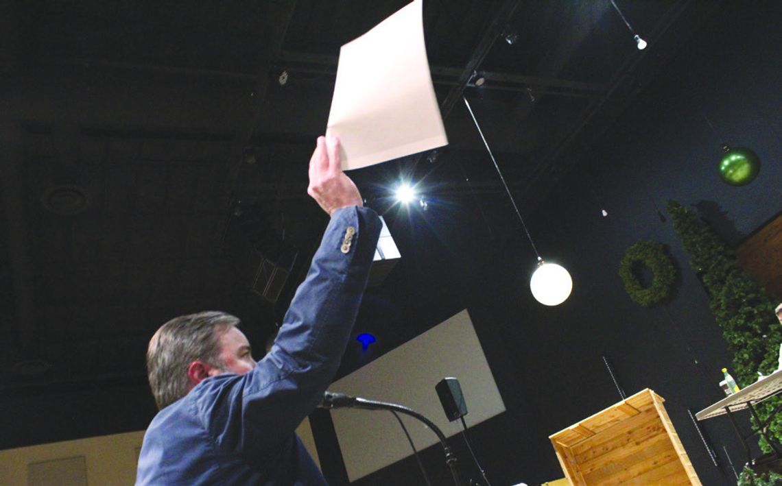 Attorney Justin Schrader lifts a paper detailing a medical study as part of his opposition to the proposed quarry before Asphalt Inc. representative Ben Liggett Dec. 10 during the public meeting in Burnet. Raymond V. Whelan/Bulletin
